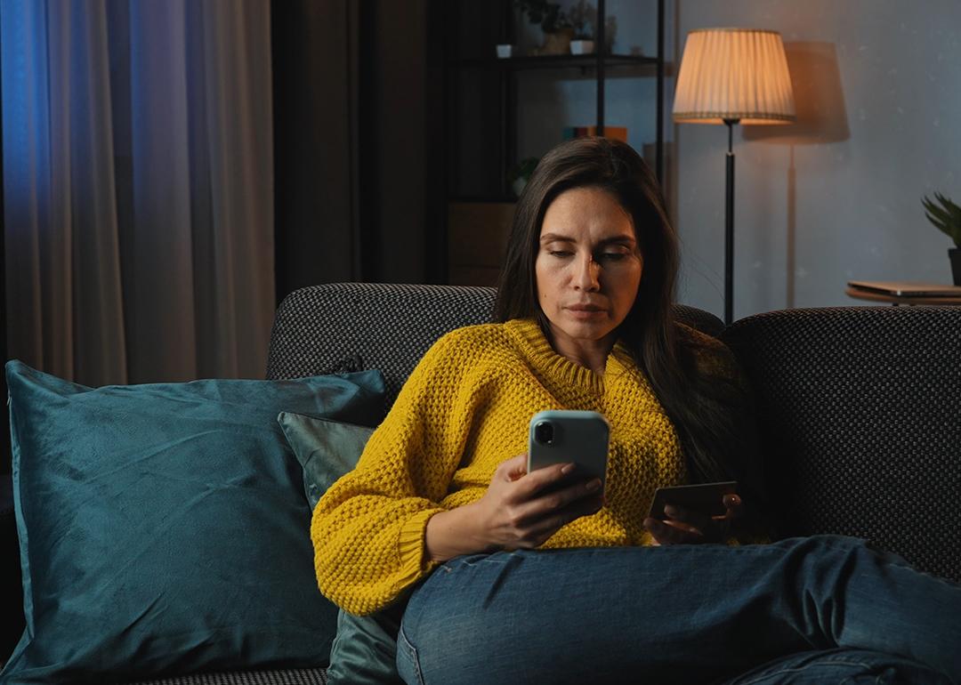 A middle-aged woman at home purchasing online using her credit card.