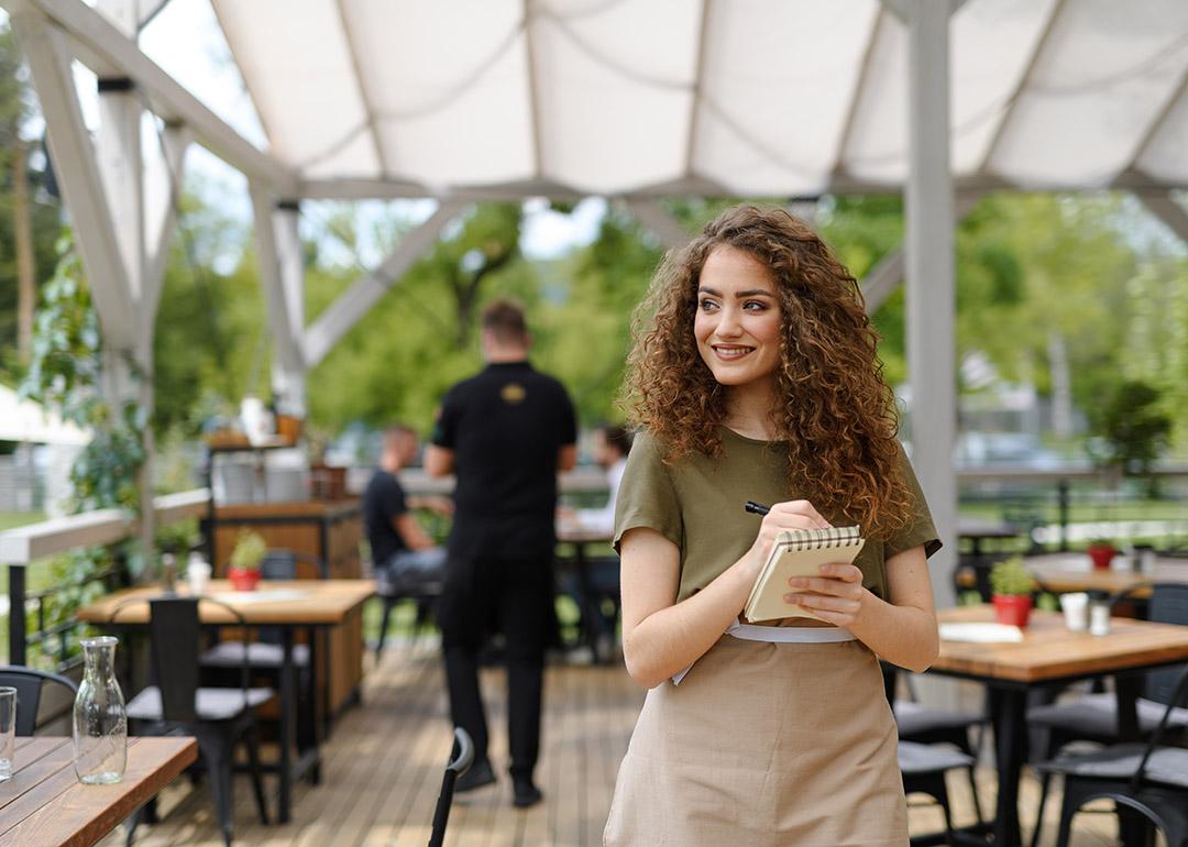 A waitress standing in a restaurant terrace after writing down an order.