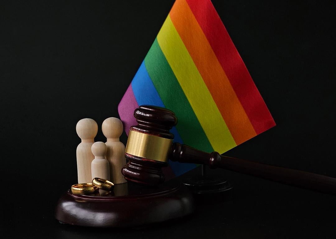 An LGBTQ+ rainbow flag with a figure of a family and judge's gavel as a concept of same-sex divorce.