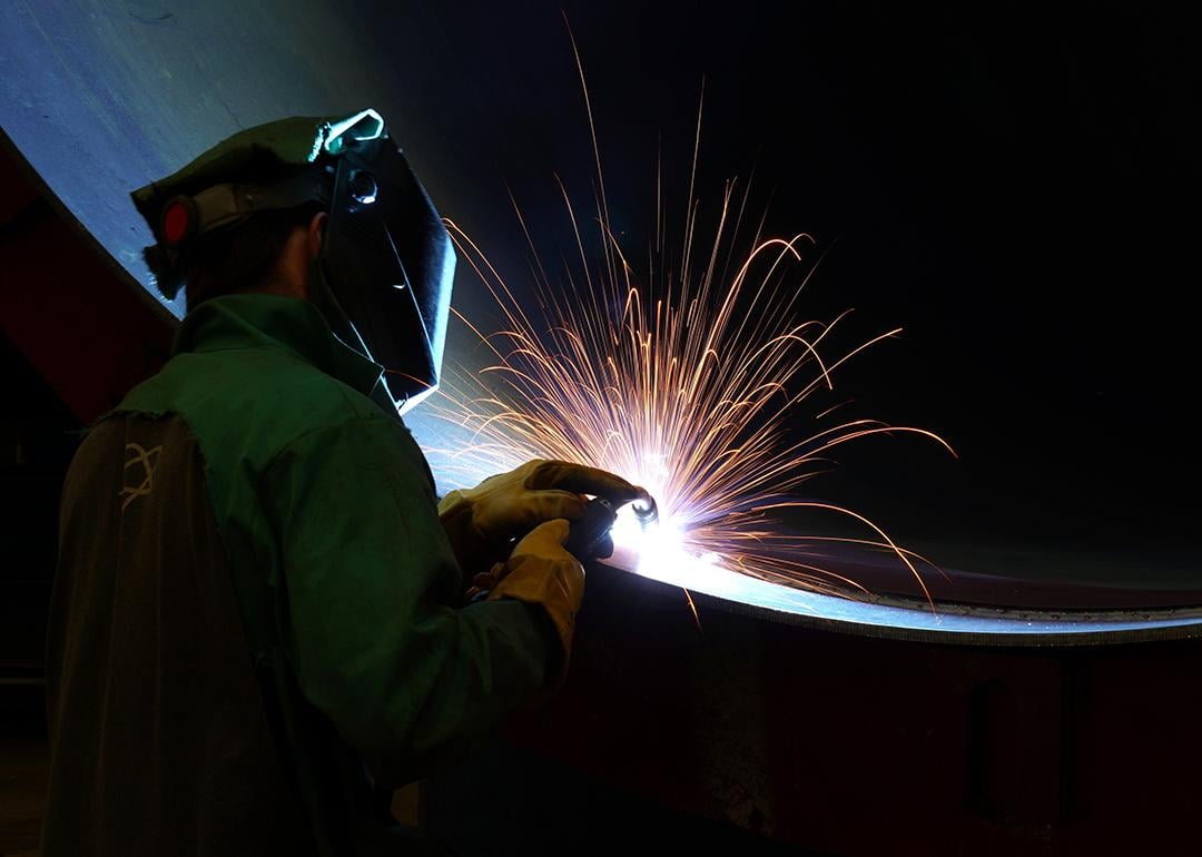 A worker welding a very large steel pipe.