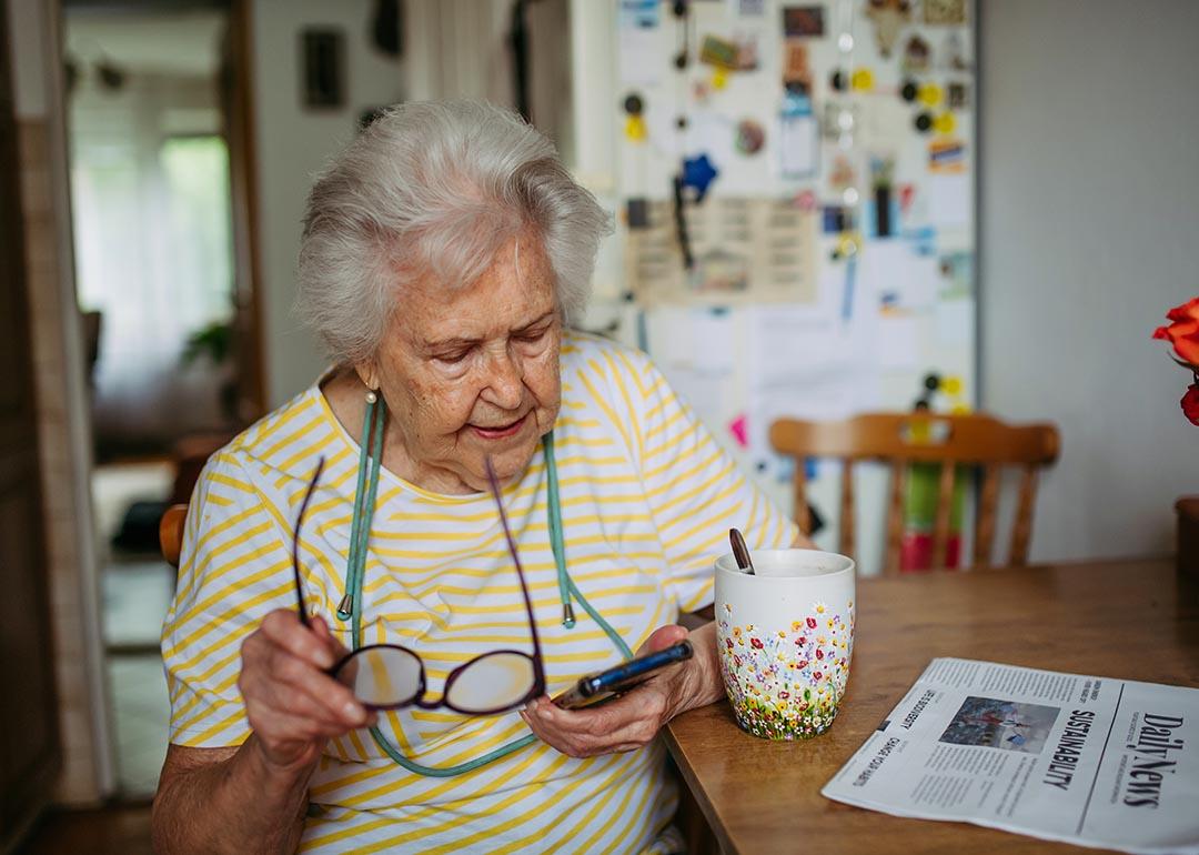 An elderly woman using a smartphone at home.