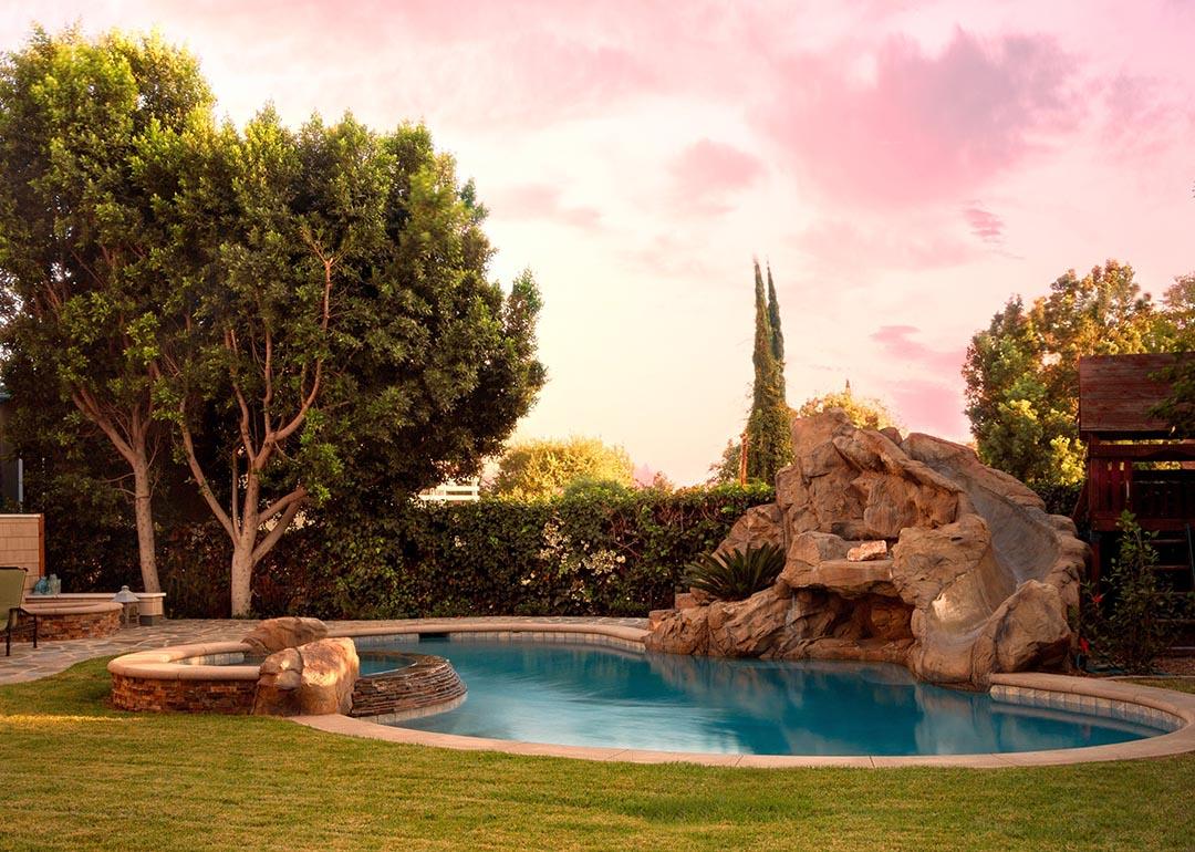A modern backyard pool with rock waterfalls and slide.