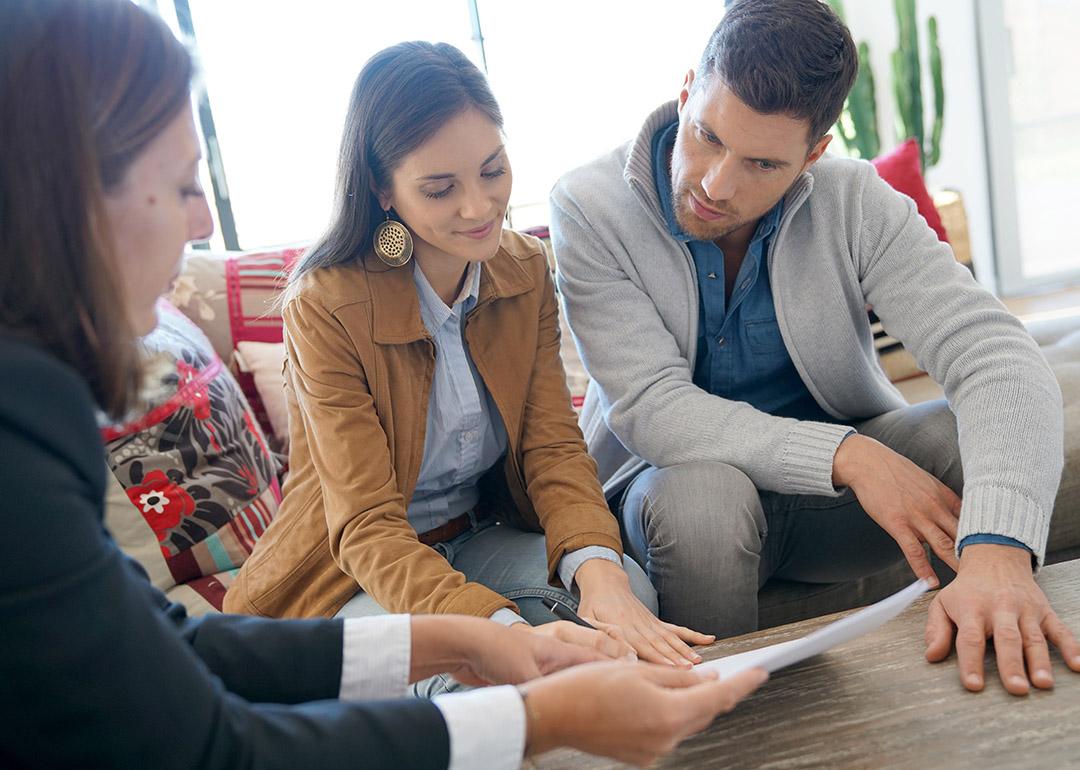 A couple reviewing a home investment contract with supervision from a financial advisor.