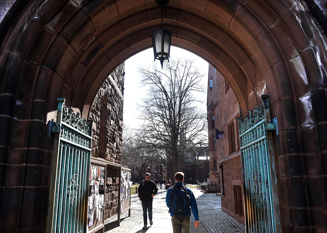 Students passing through an entrance to Yale University's old campus in New Haven, Connecticut, USA. 