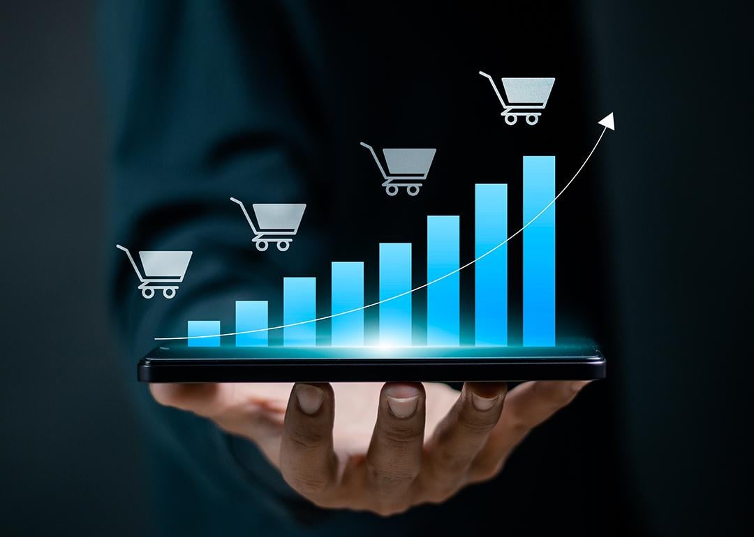 Person holding a device projecting a digital bar chart depicting growing sales.