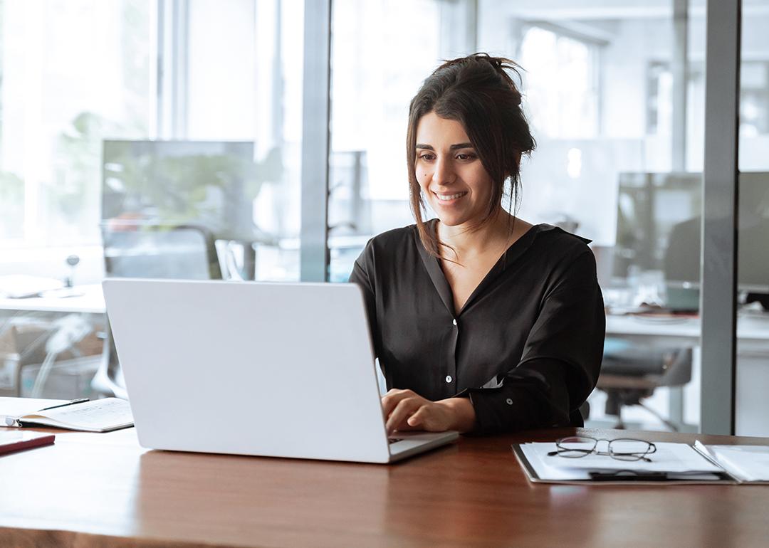 A focused young businesswoman working with a laptop in an office.