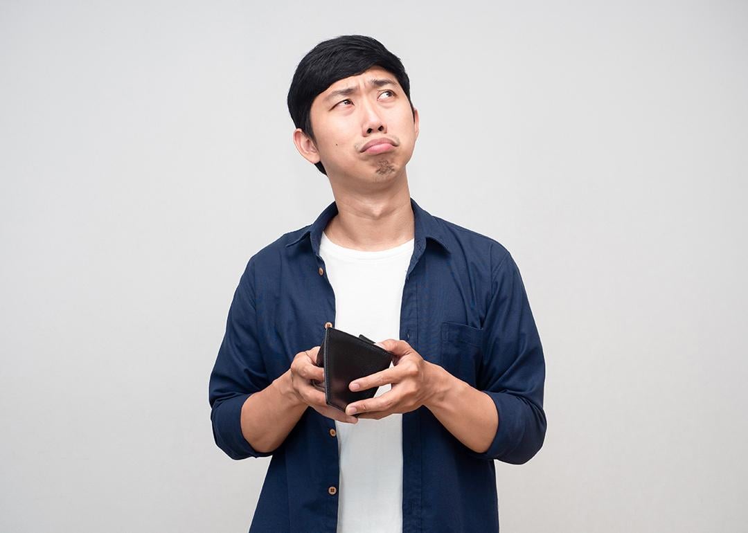 A frugal man confusingly holding an empty wallet.