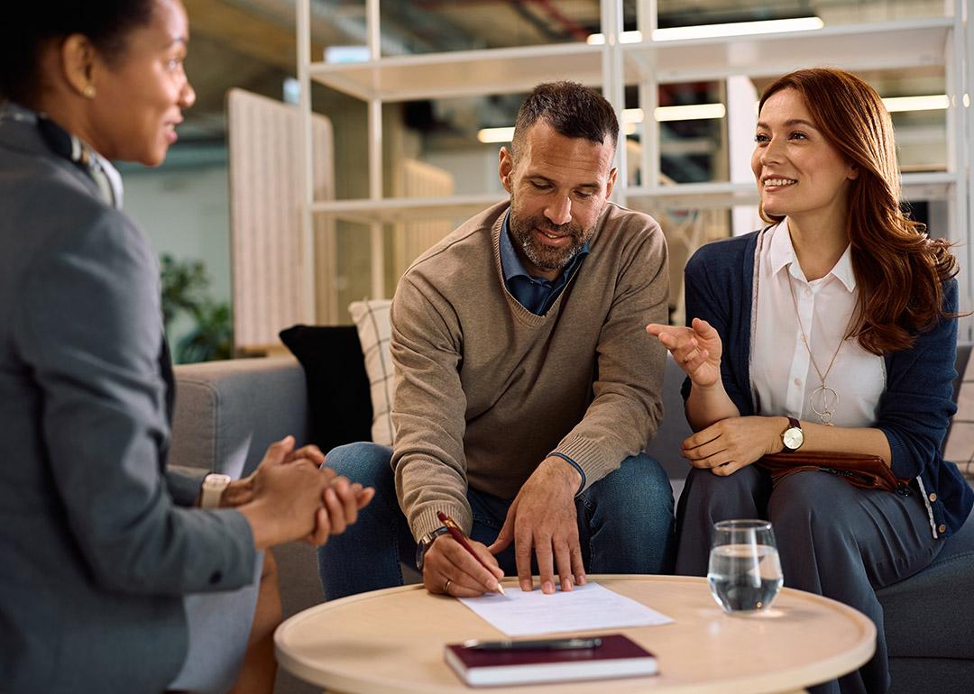 A couple meeting with a financial advisor for an insurance's contract signing.