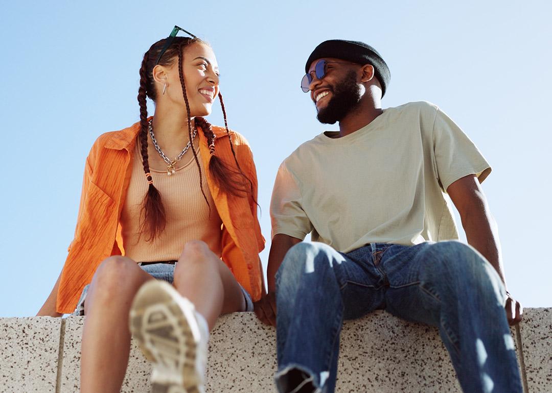 A couple bonding together while enjoying in a sitting wall outdoors.