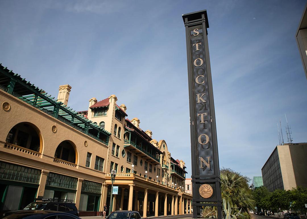 View of a street in downtown Stockton with a tall metallic sign with the city name vertically displayed in 2026.