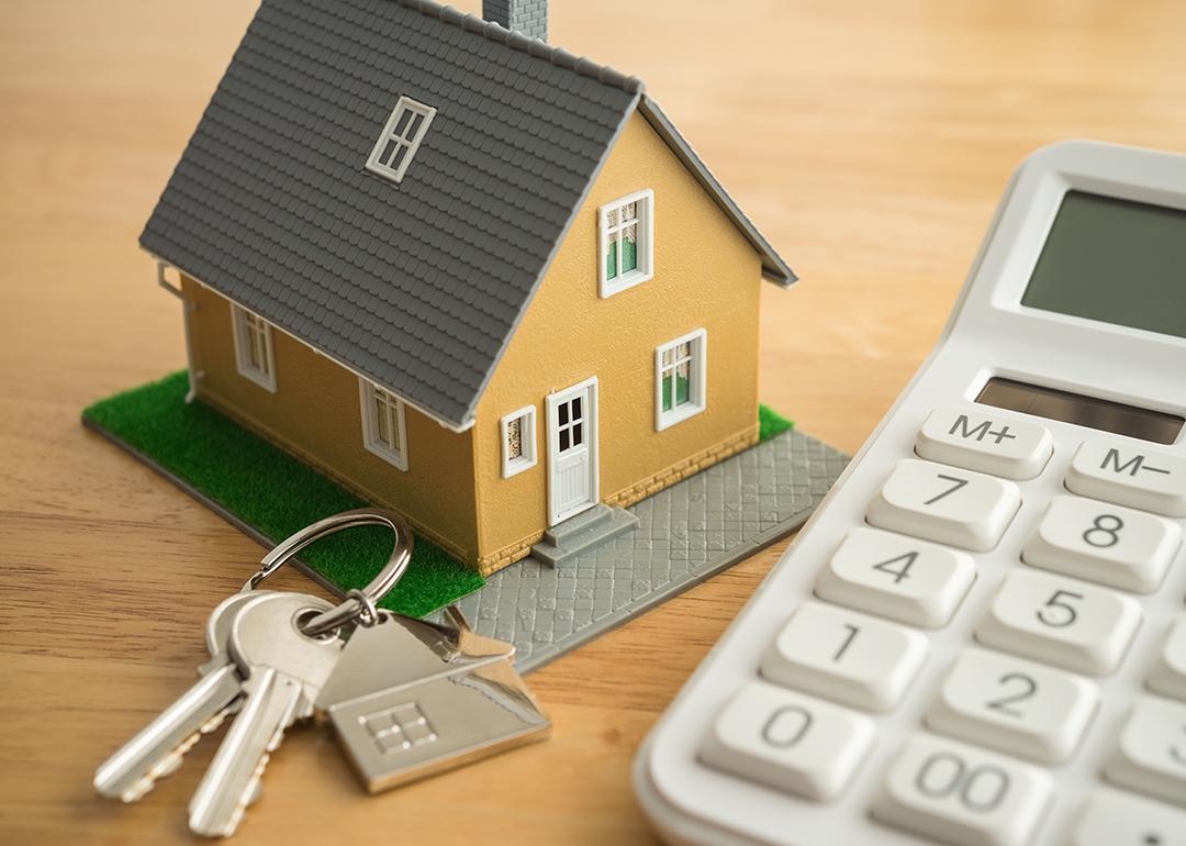 A small house model, house keys, and a white calculator as a concept of calculating rent.