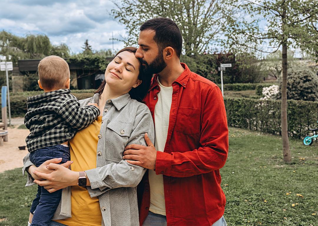 A young family of 3 spending time together outdoors in a park.