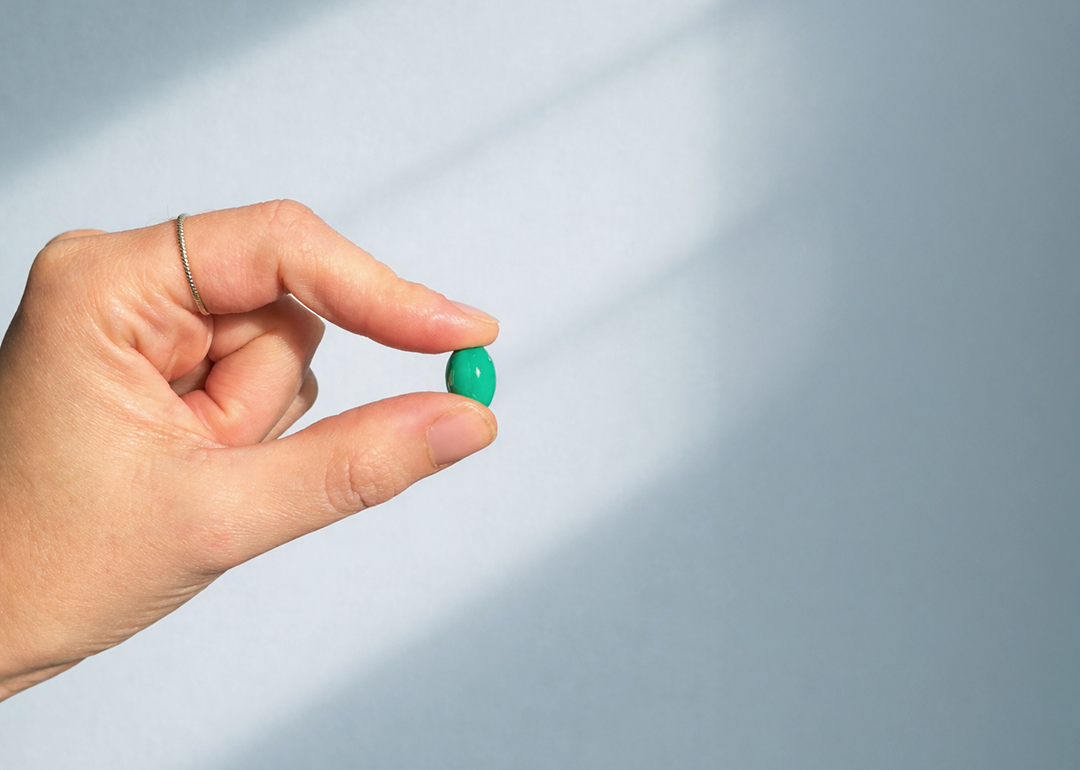 Hand holding a small pill against the sunlight