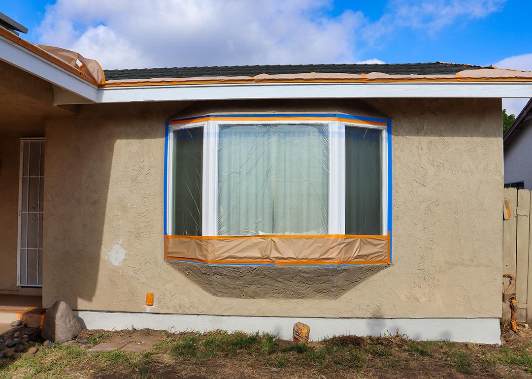 A portion of a house for sale covered with protective plastic for a repainting job.