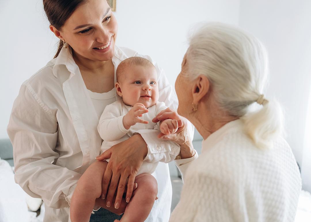 A grandmother looking at her adult daughter and newborn granddaughter.