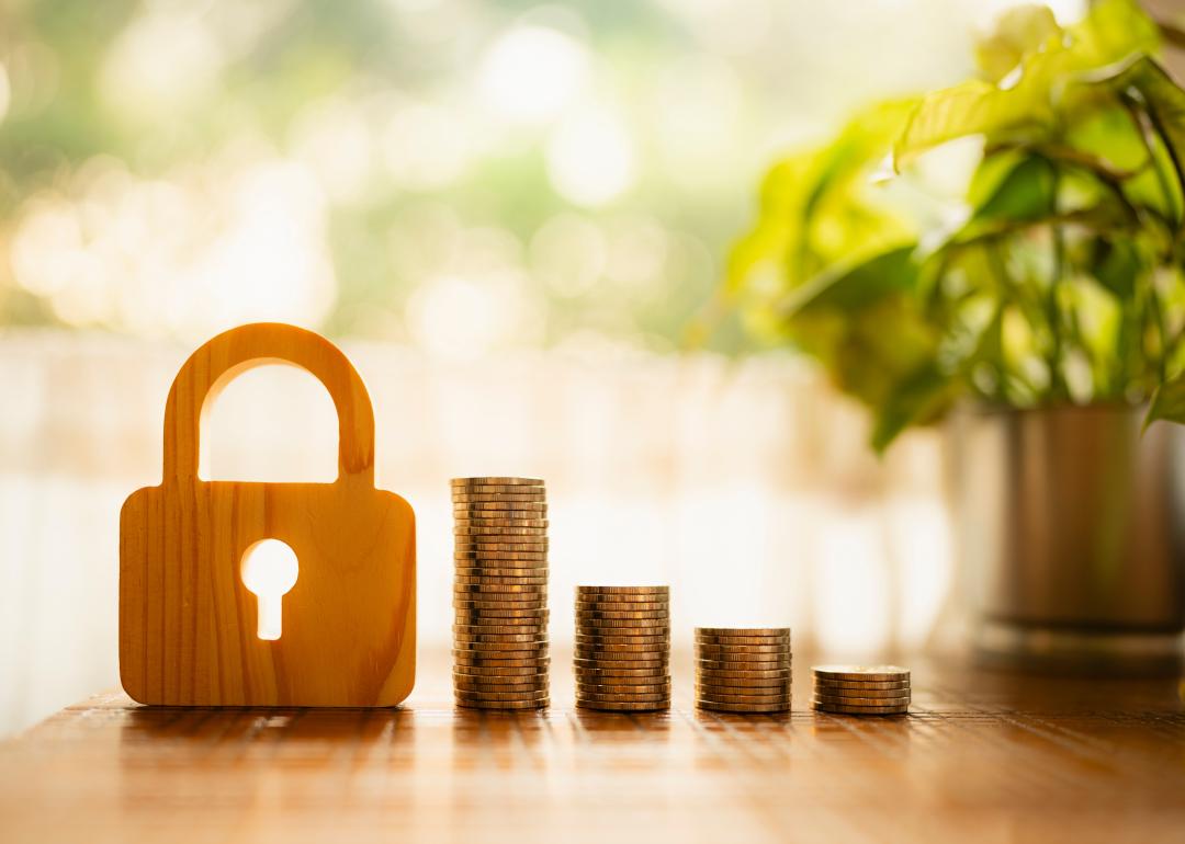 A wooden lock model and stacks of coins in descending height. 