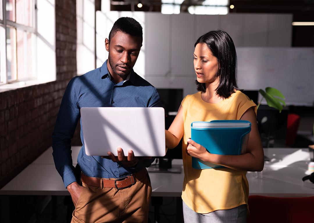 Two colleagues standing in an office discussing a task together.
