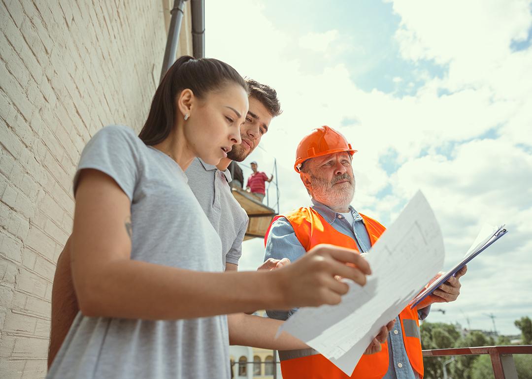 A foreman showing a young couple the plans to their new home.