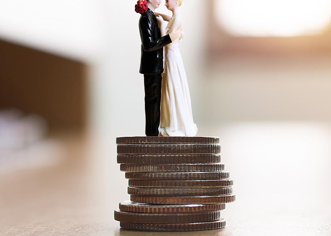 Figure of a married couple on top of a stack of coins as a concept of saving for a wedding.