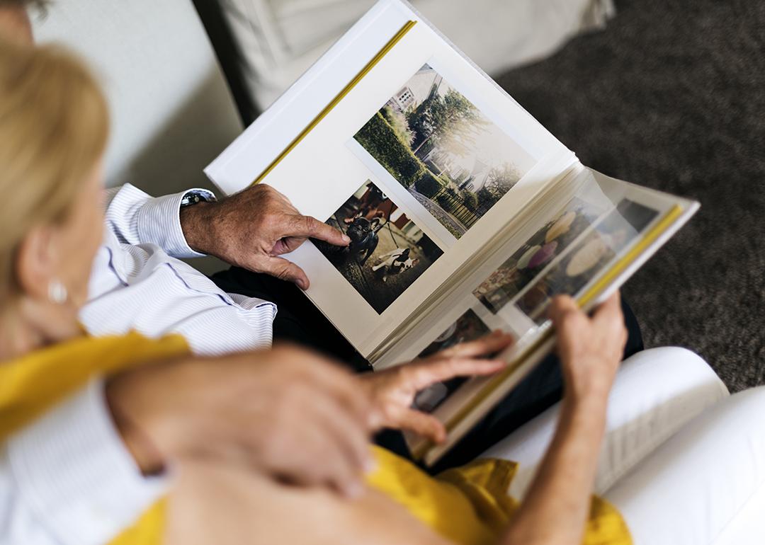 An elderly couple browsing and looking through a photo album.