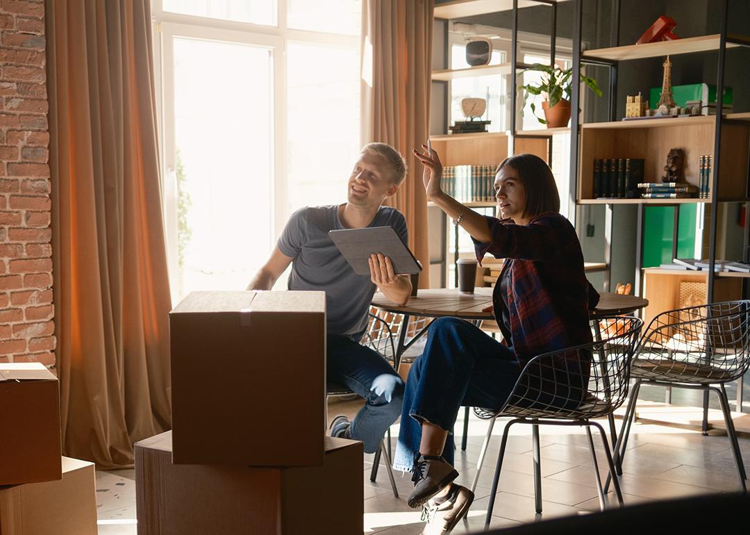 A couple surrounded with packed boxes discussing room organization after moving in.