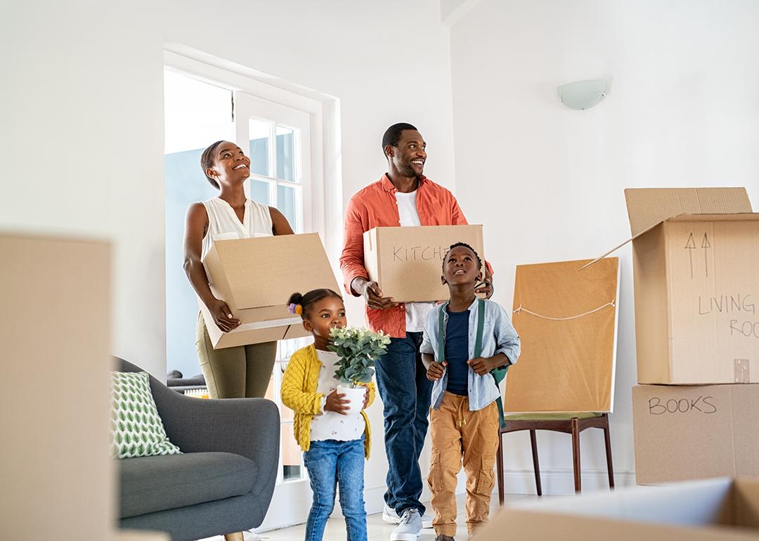A happy family of four moving into their new home, surrounded by cardboard boxes labeled for different rooms.