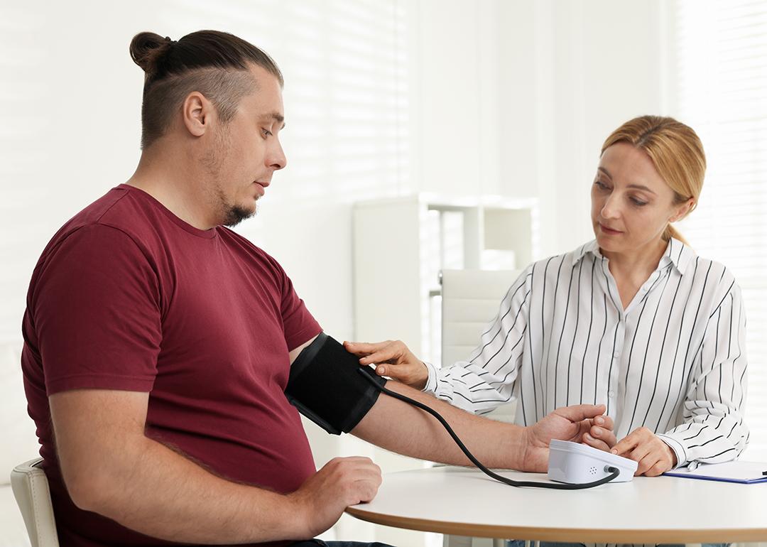A nutritionist measuring a patient's blood pressure using a manual sphygmomanometer in a clinic. 