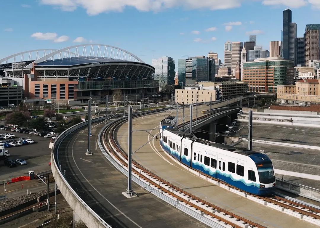 A Sound Transit Link light rail train, with the Lumen field and Seattle skyline in Washington, USA.