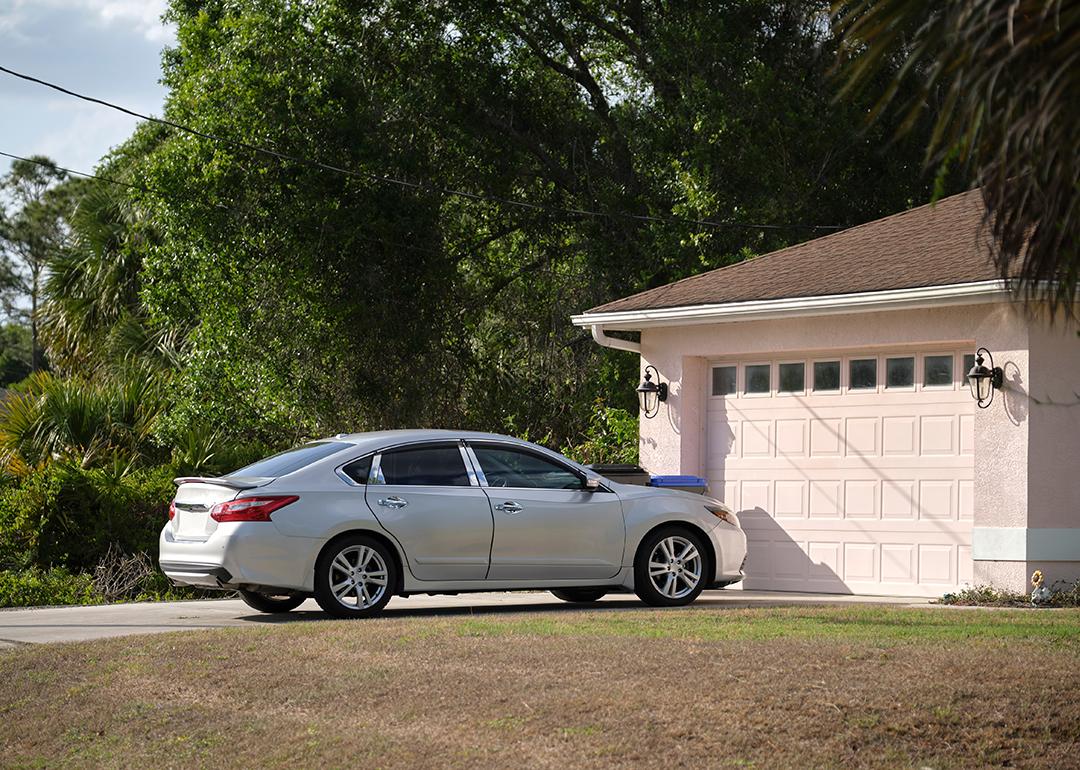 A car parked in front of a modern American house's garage. 