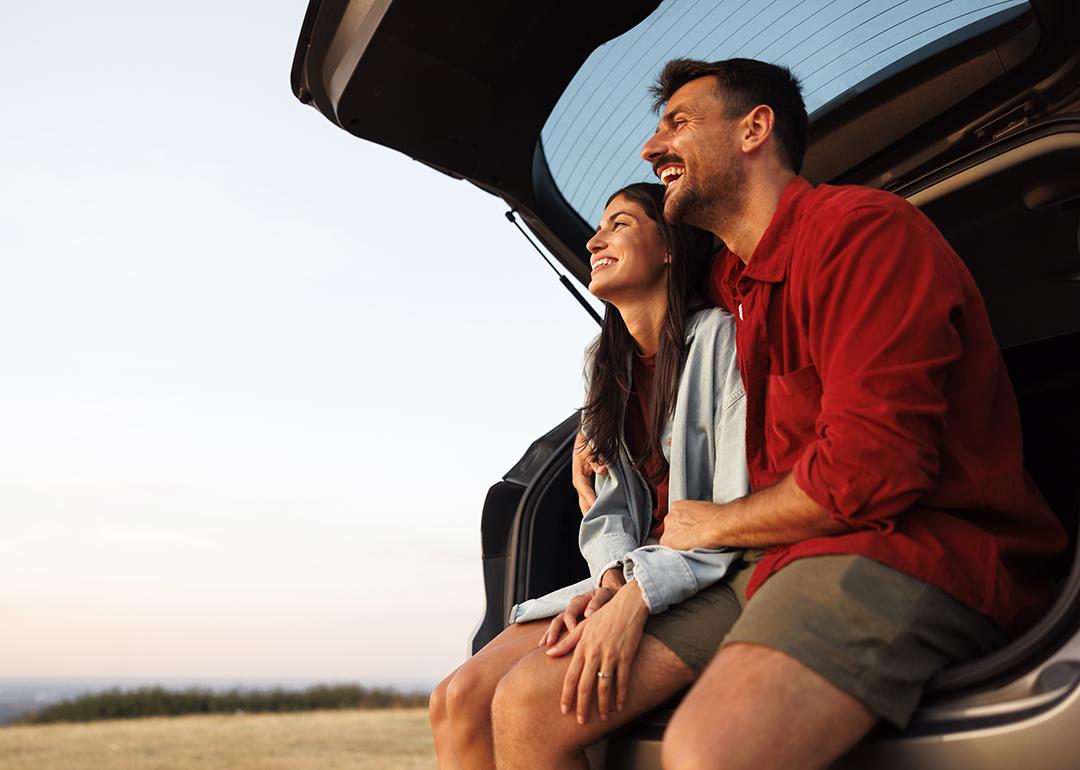A couple taking a break at their car's trunk from a long drive trip.