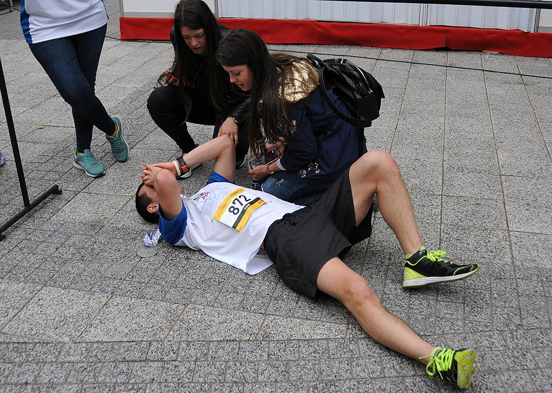 A half-marathon runner collapsing on the ground after crossing the finish line.