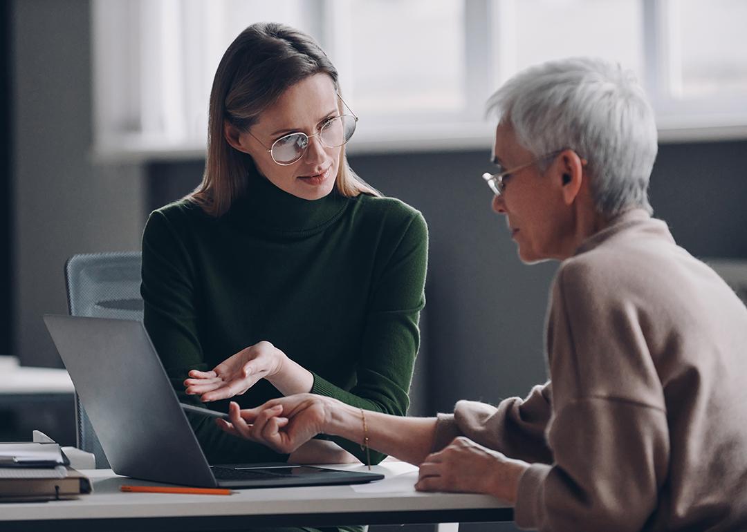 A financial advisor discussing plan options for a life insurance with an elderly client in the office.
