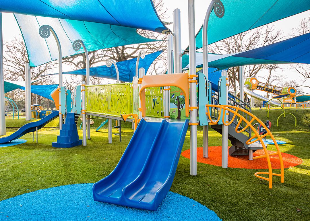 A colorful, modern playground with slides, bridge, climbing stairs, and a canopy.