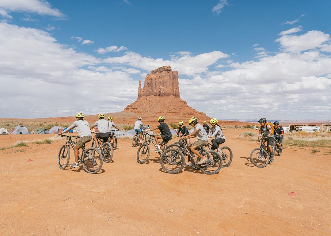 A cycling group in the Arizona desert, specifically within Monument Valley.