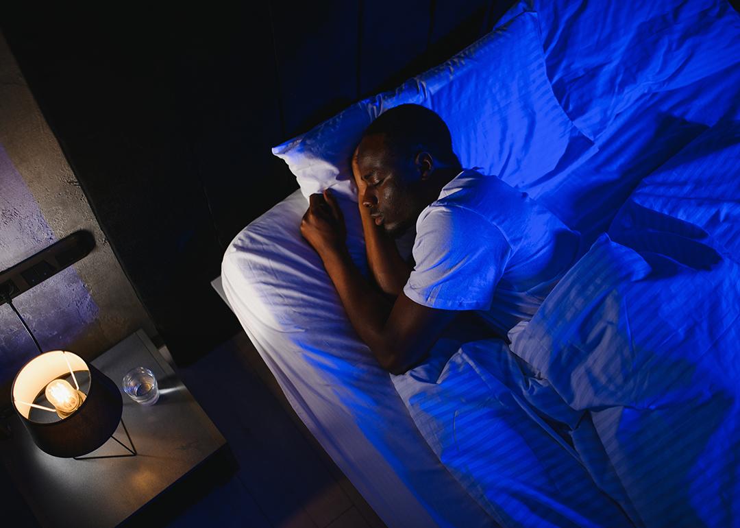 A person enjoying a night's sleep under his bed's linen sheets.