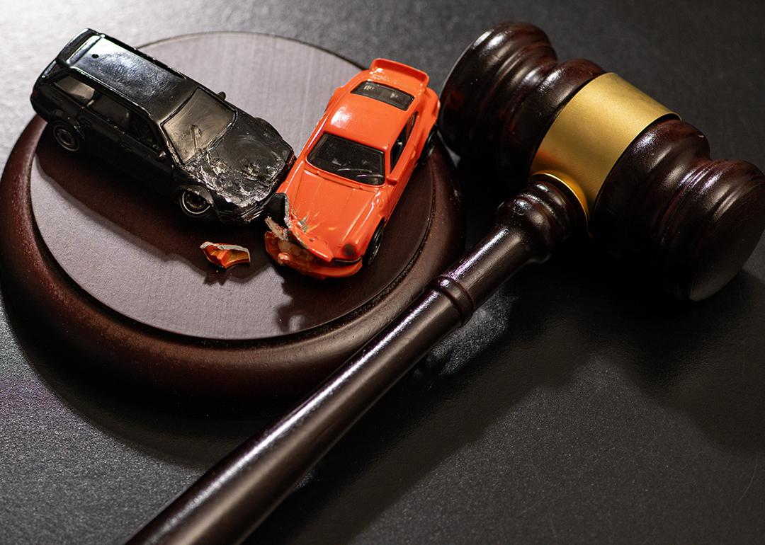 Figures of crashed cars and a gavel as a concept of traffic court civil litigation.