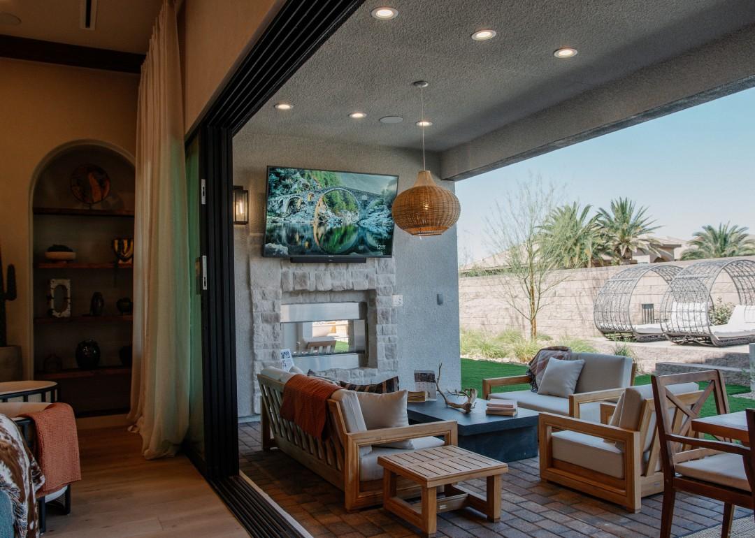 A modern covered patio in a backyard with extended living area, outdoor television, and fireplace. 