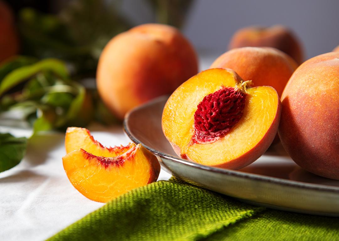 A freshly cut yellow peach with a red pit.