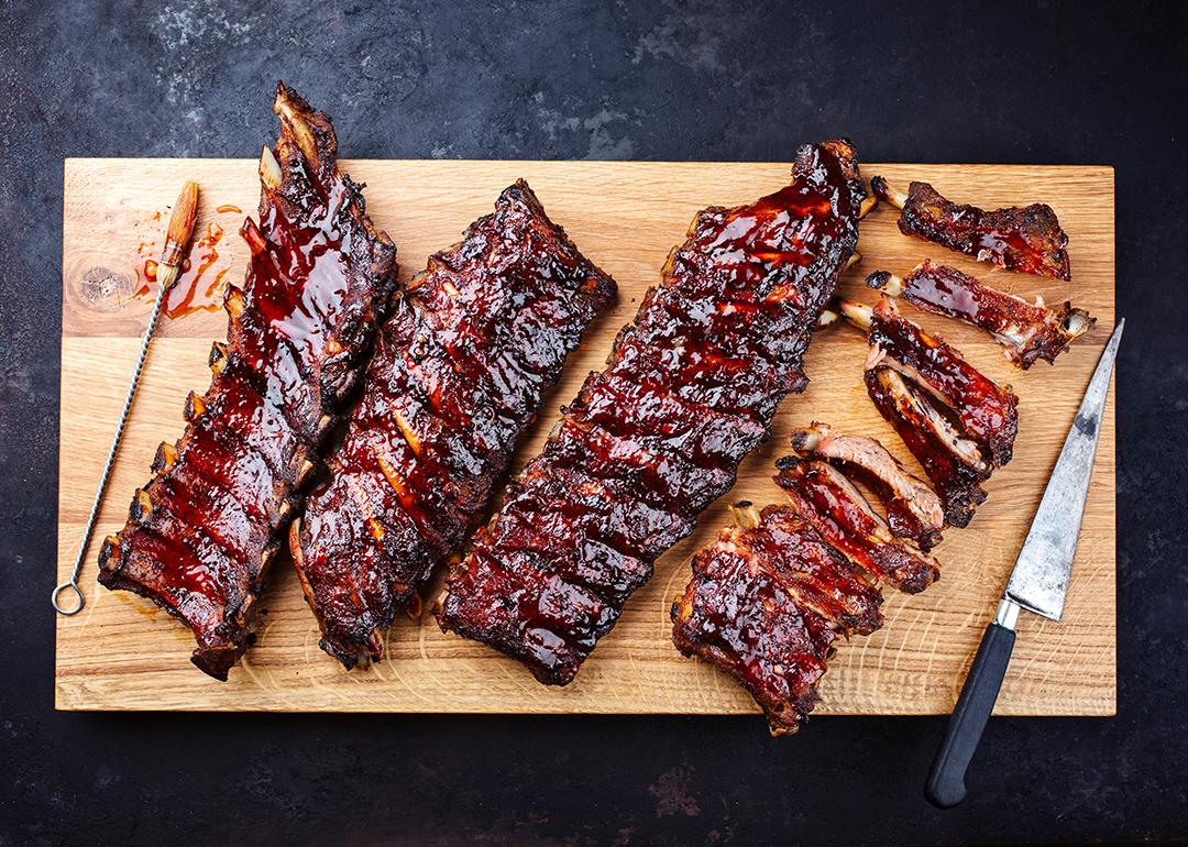 Slabs of freshly barbecued ribs sliced on a wooden cutting board.