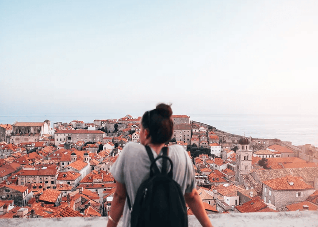 A young tourist looking over red-brownish roofs from Old Town in Dubrovnik, Croatia.