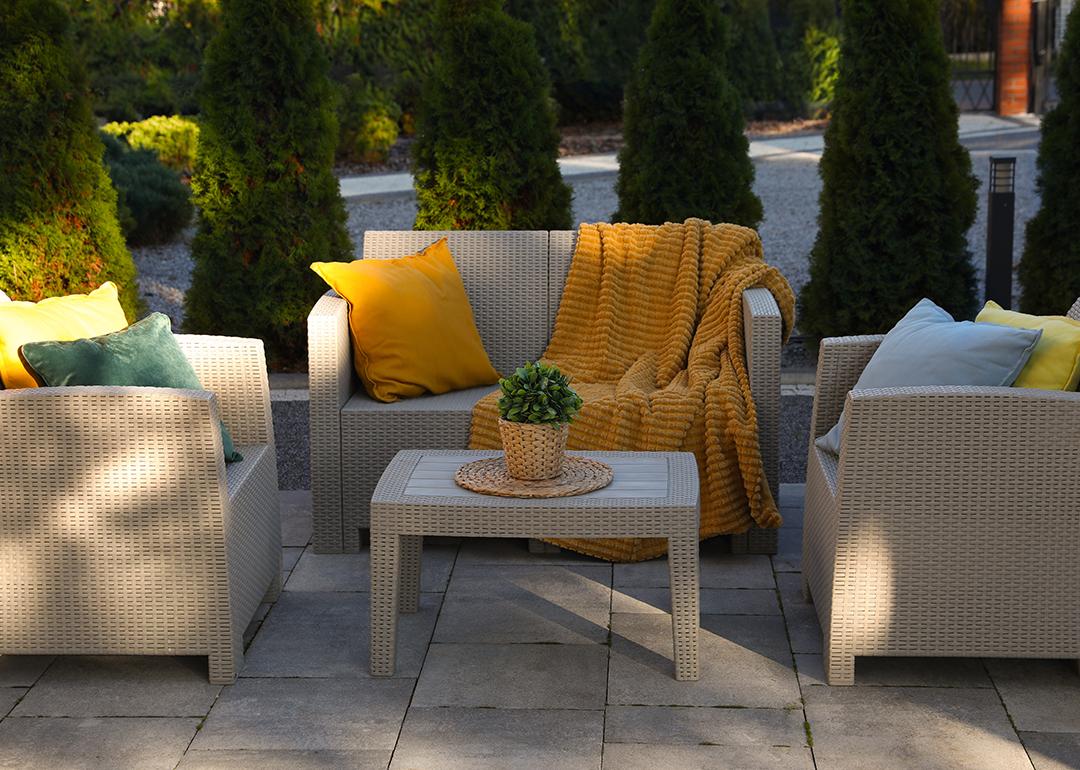 An outdoor rattan garden furniture set with yellow and cream motifs.