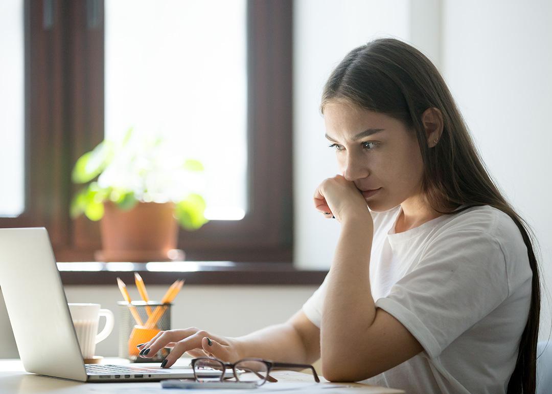 A person appearing to be suspicious while reading from a misleading online content from a laptop.