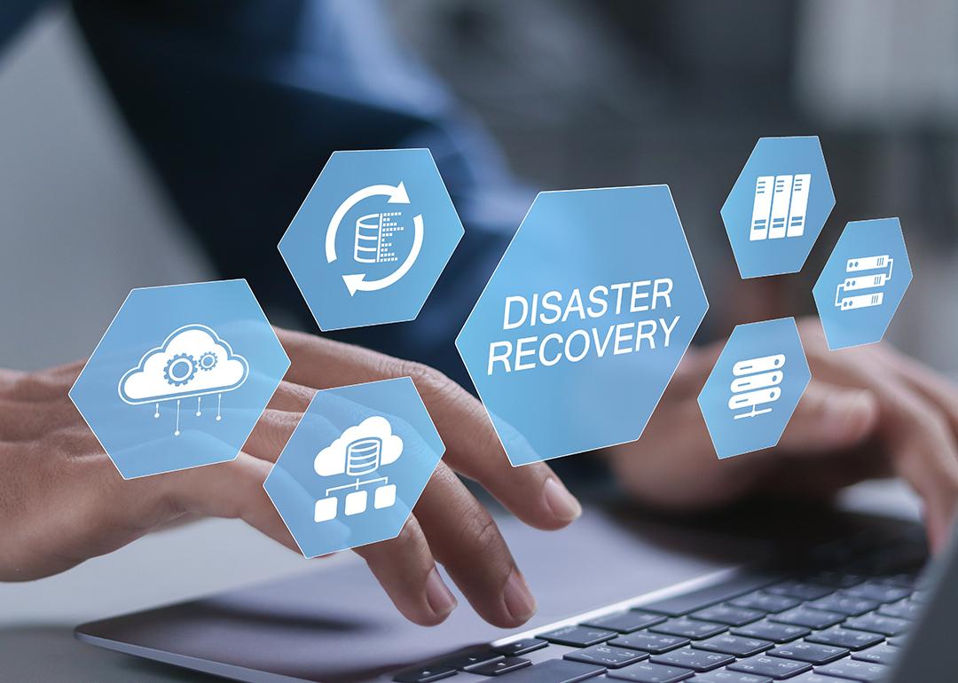 Businessman typing over a keyboard illustrated with conceptual graphics for a cyber disaster recovery system.