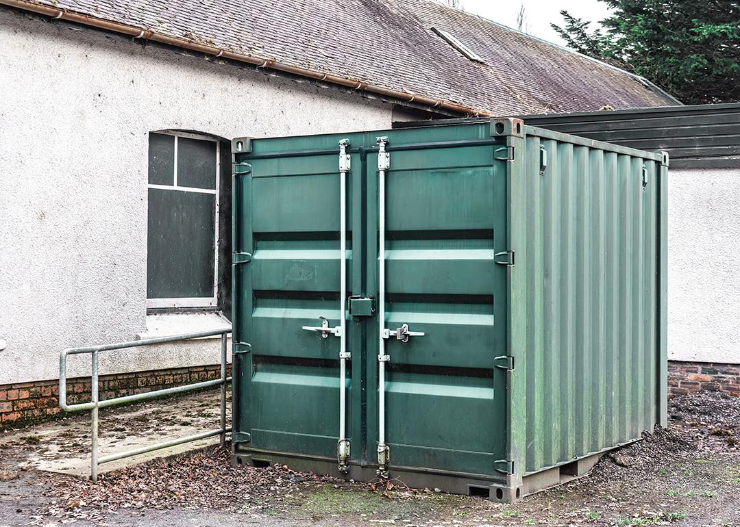 A large steel storage container positioned outdoors beside a building.