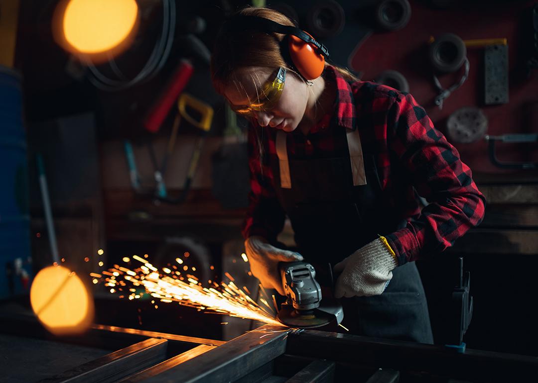 A tradeswoman working with an angle grinder.