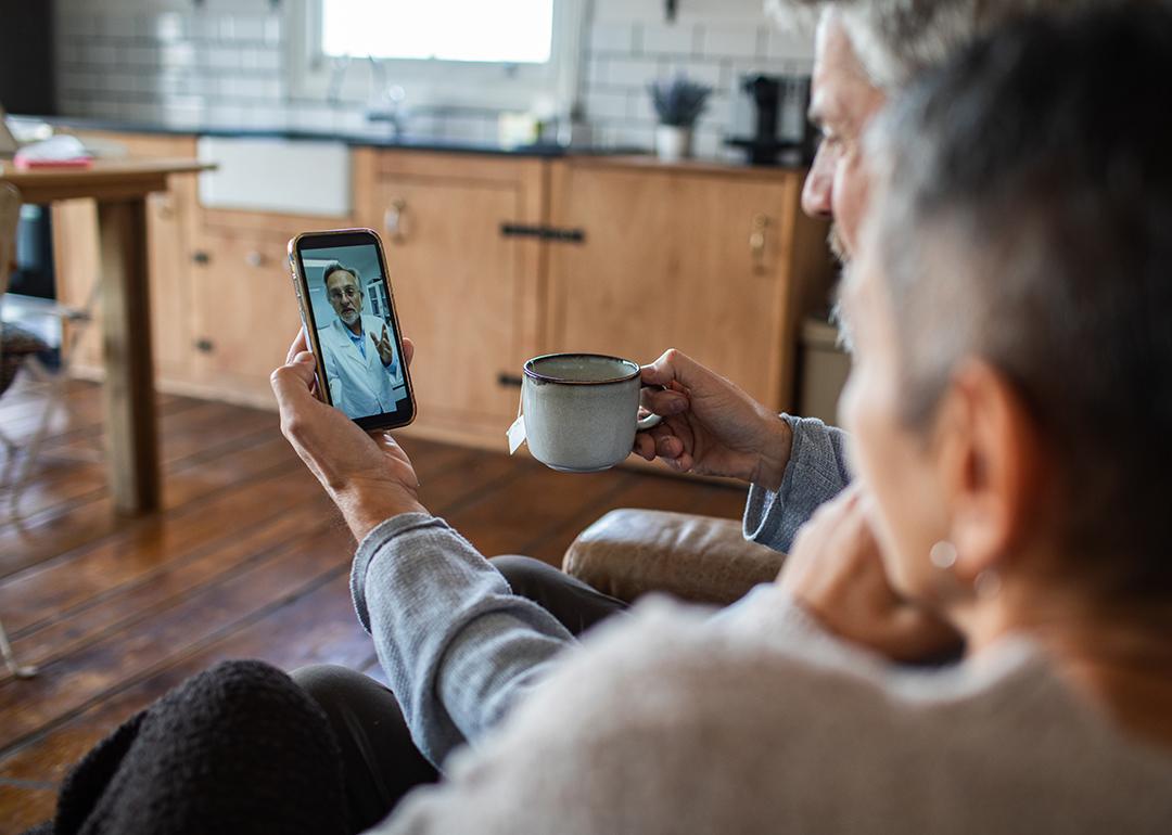 An older couple in a telehealth call at home with their doctor.