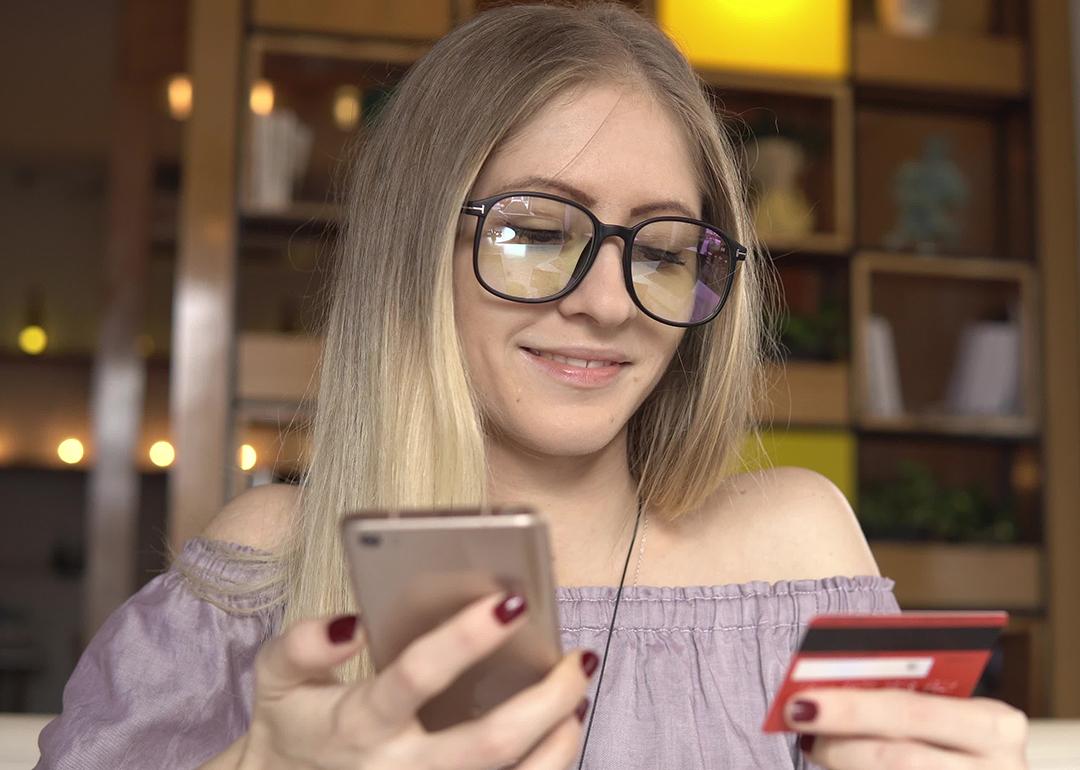 A woman shopping online using her phone and credit card.