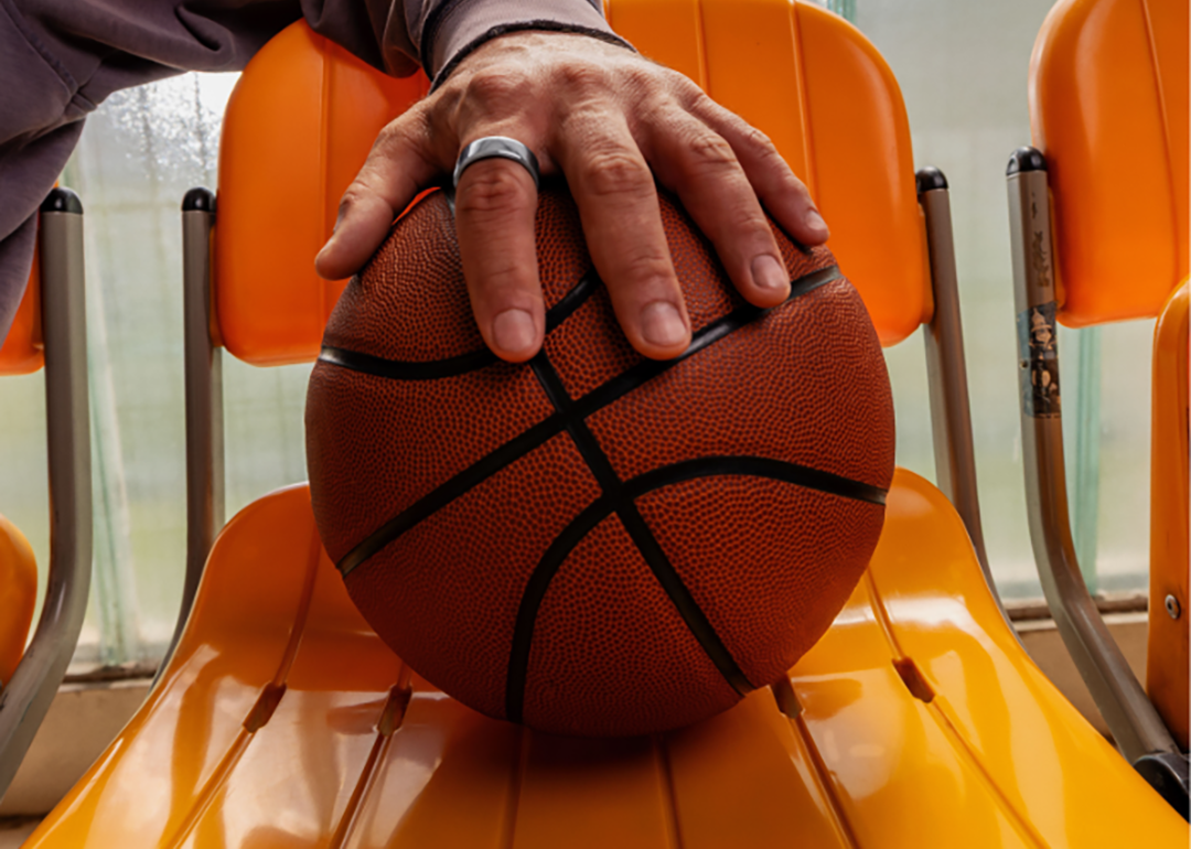 A player's hand wearing an Oura ring placed over a basketball.