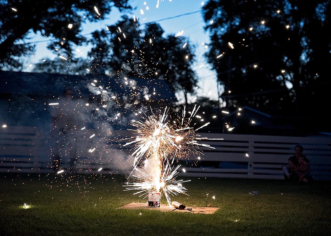 Fireworks going off at a backyard picnic during Fourth of July.