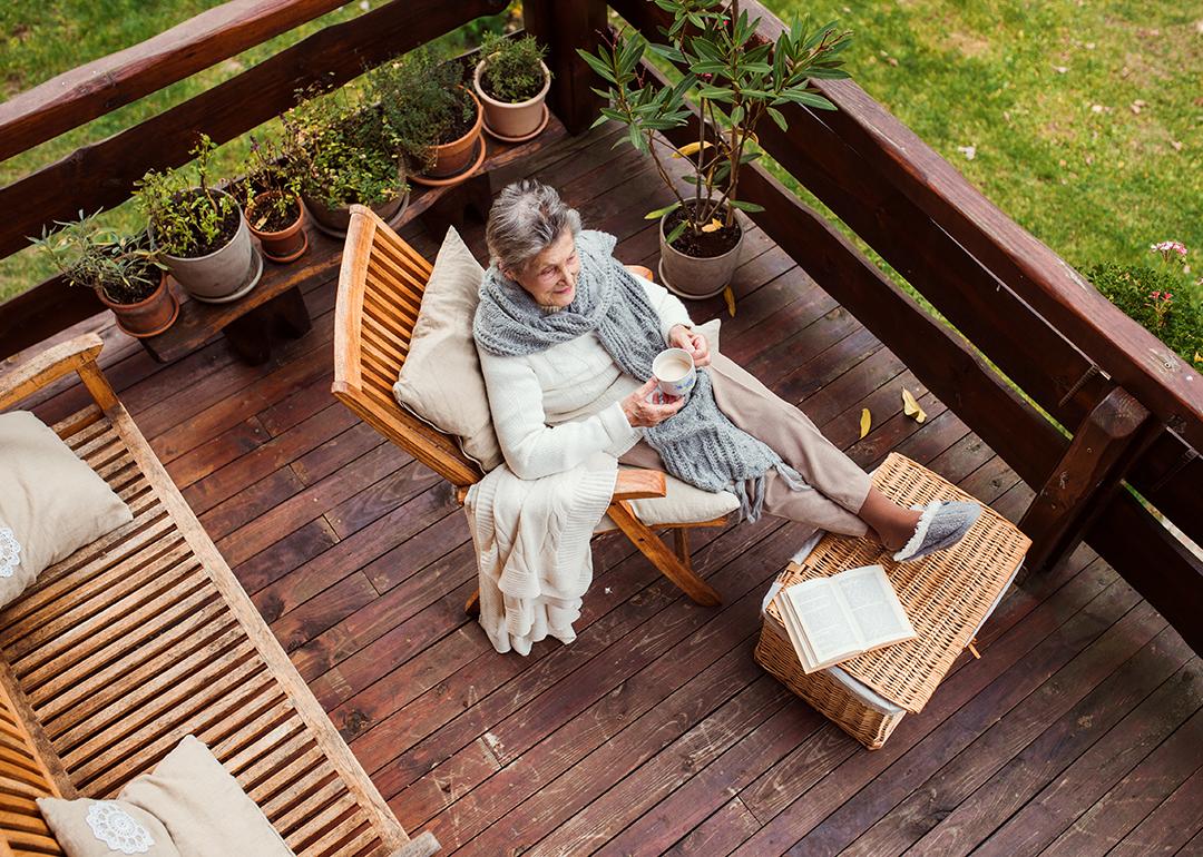 Top view of an elderly woman with a book while sitting relaxingly by her home's terrace.